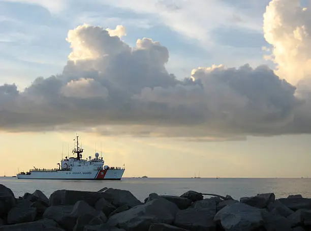 A photo of a Coast Guard Cutter in front of a sunset