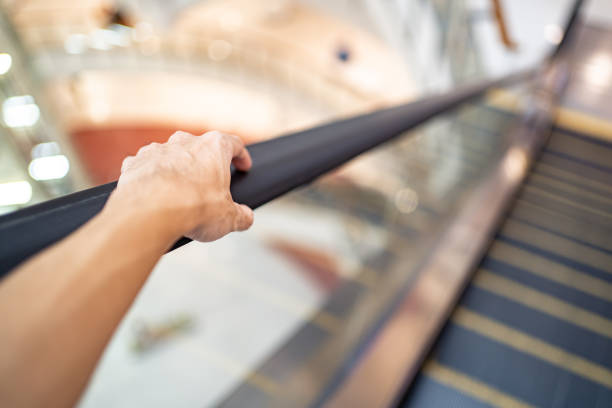 Hand holding escalator's handrail in shopping mall