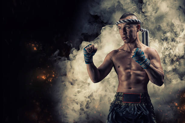 Portrait of a boxer of mixed martial arts standing on the background of smoke and fire. The concept of sports, mma, kickboxing. stock photo