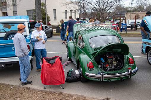 Monroe, Georgia - March 14, 2020: An owner stands talking with a visitor next to a restored Volkswagen beetle, one of  hundreds of classic automobiles on display during the 15th Annual Memories in Monroe car show downtown.