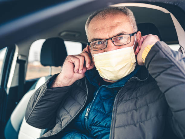 istock COVID-19, Mature man putting on disposable face mask 1212801611