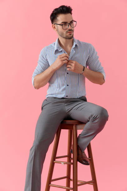 istock Eager smart casual man looking away unbuttoning his shirt 1212801625