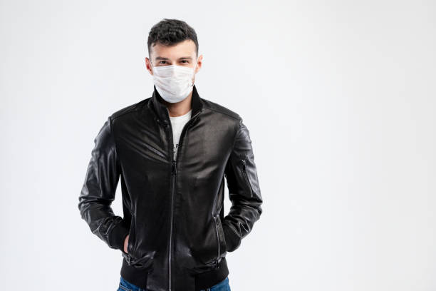 使い捨てフェイスマスク付き黒いジャケットを着たハンサムな白人の若者。ウイルスおよび感染に対する保護。デザイン用のスペースをコピーします。 - gauze healthcare and medicine disposable bandage ストックフォトと画像