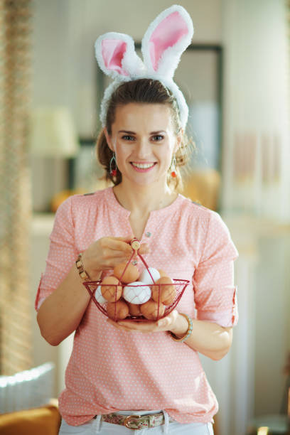 istock smiling modern woman showing basket with eggs for coloring 1212802074