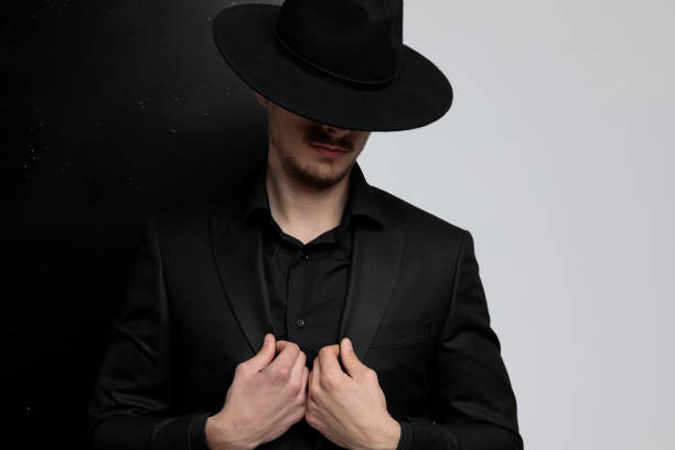 istock Mysterious fashion model adjusting his jacket while hiding his eyes 1212803568