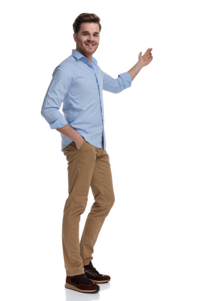 istock Happy casual man presenting and smiling with hand in pocket 1212804358