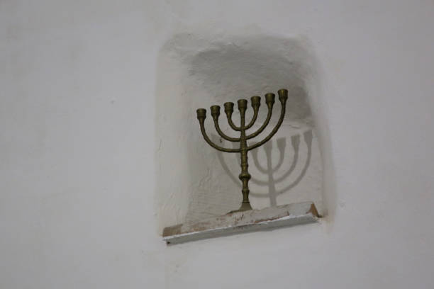 istock menorah and it's shadow in a niche in a white wall 1212806109