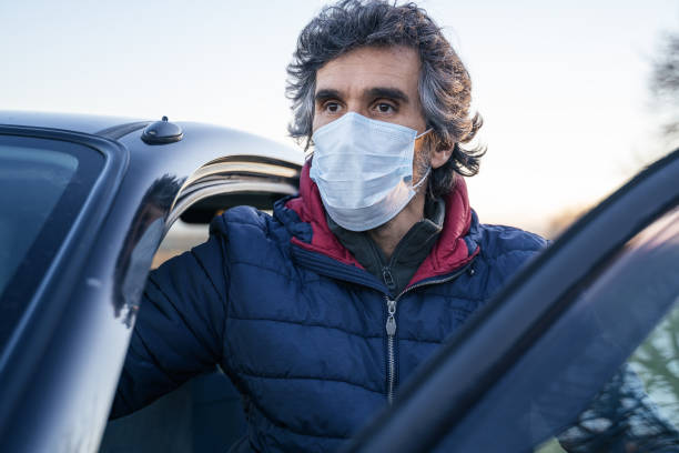 istock Active mature man taking his car to go to work. Driving with a protective mask on the face. 1212811483