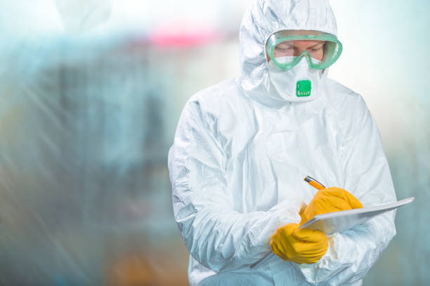 istock Female epidemiologist in protective clothing writing research report 1212812203