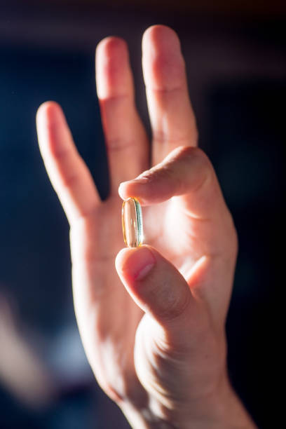 istock Pill capsule with transparent oil solution in fingers.Panacea for viruses and diseases 1212812241
