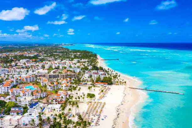 Aerial drone view of beautiful caribbean tropical beach with palms and straw umbrellas. Bavaro, Punta Cana, Dominican Republic. Vacation background