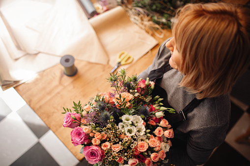 Beautiful female florist arranging bouquet in her flower shop.