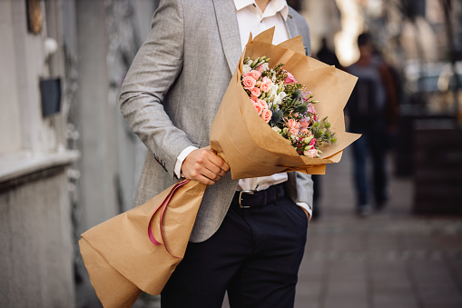 Young man standing and holding beautiful bouquet of fresh flowers.