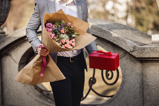 Young man standing and holding beautiful bouquet of fresh flowers.