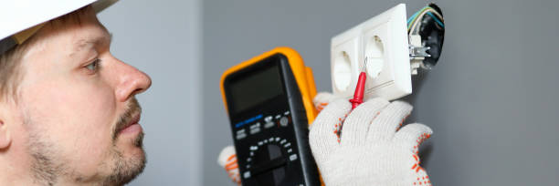 istock Electrician in helmet measures level electricity 1212820038
