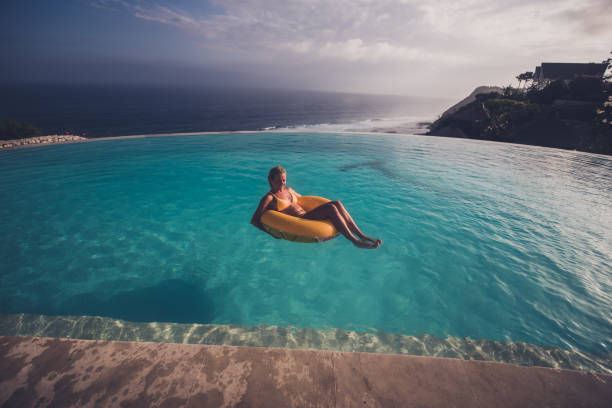istock Happy woman relaxing in infinity pool on float. 1212824544