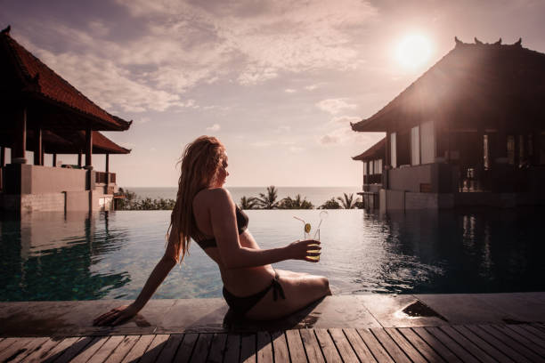 istock Blondie woman drinking cocktail at swimming pool. 1212825152