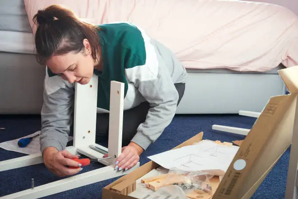 woman building flatpack furniture in her bedroom