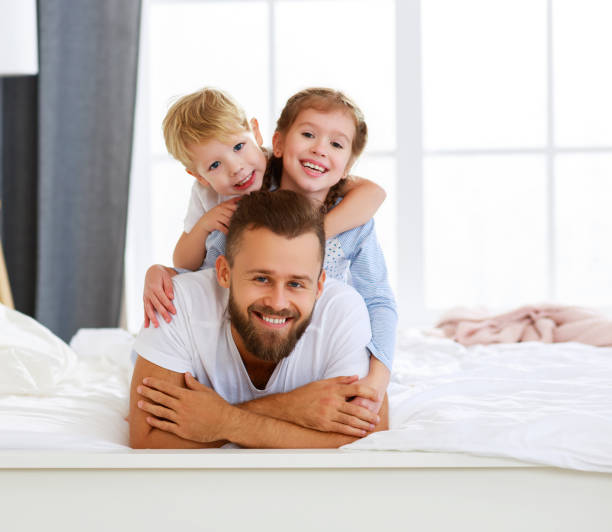 istock Happy father with kids lying on bed 1212829306