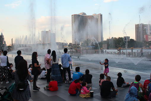 Bangkok, Thailand - December 1, 2019: People watch fountain show at the riverside of IconSiam department store, one of the largest shopping malls in Asia.