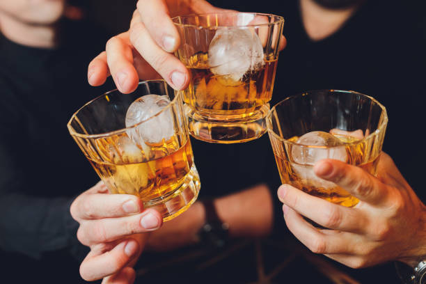 istock Clinking glasses with alcohol and toasting, party. whiskey ice 1212840375