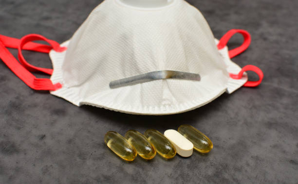 オメガ3とビタミンd、カルシウムとマグネシウムカプレット、保護マスク、呼吸器と魚油カプセル。免疫力と抗コロナウイルスの概念を高める。 - fish oil pill healthy lifestyle protection ストックフォトと画像