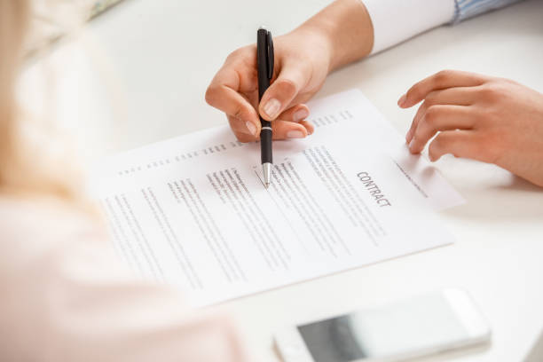 istock Travel agent at office with senior client signing contract discussing terms close-up 1212840957