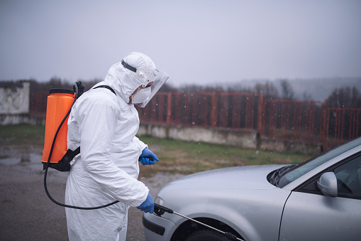 Photo of disease control service staff disinfect a car in front of geographic border to prevent spread COVID-19.