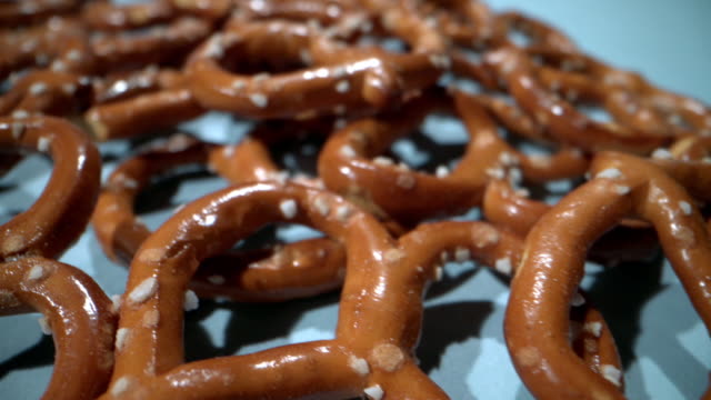 Ultra Close-Up Macro Slow Moving Shot of Delicious Salted Mini Pretzels Twists Knots Snacks against a Blue Background