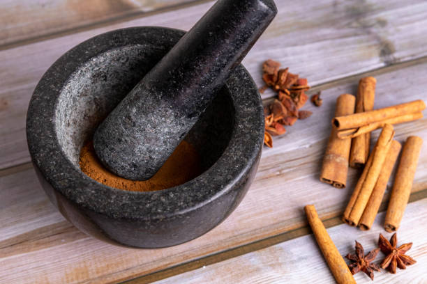 mortero y pestle con hierbas y especias que se acuestan sobre la mesa de madera junto a ella. - mortar and pestle wood healthcare and medicine jar fotografías e imágenes de stock