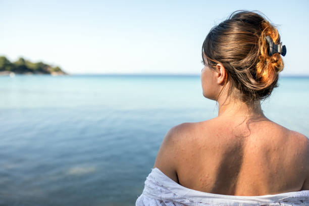 Rear view of young lady enjoying the sight of beautiful sea
