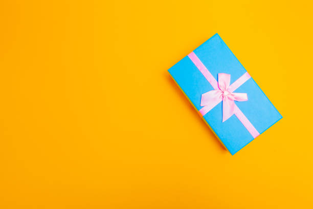 istock blue box with a ribbon on a yellow background. 1212852101