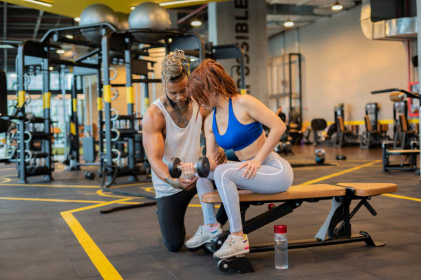 istock Young woman training in a gym with her personal trainer 1212852271