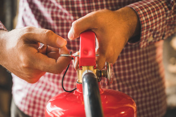 istock Close up hand Fireman using fire extinguisher fighting. Hand pulling pin of fire extinguisher 1212854702