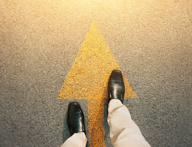 istock Feet and arrows on road. 1212861772