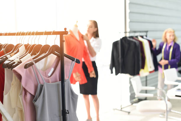 istock Fashion designer studio measuring textile material scissors cutting fabric by woman designer stylish showroom hanging clothes sewing machine and crafting tools designer working professional 1212866452