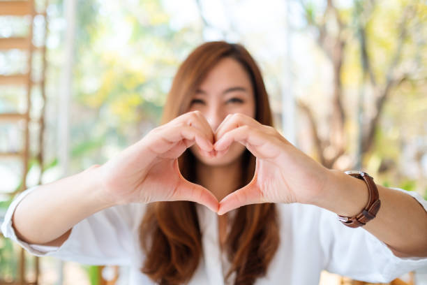 istock woman making heart hand sign with feeling happy 1212869464
