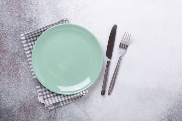 istock Empty mint plate, linen napkin, knife and fork on stone background Copy space Top view 1212870987