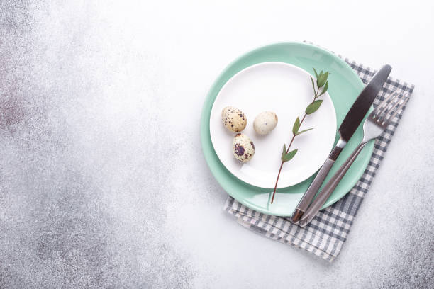 istock Easter table setting. Empty mint and white plates, linen napkin, eucalyptus leaves and eggs on stone background 1212870997