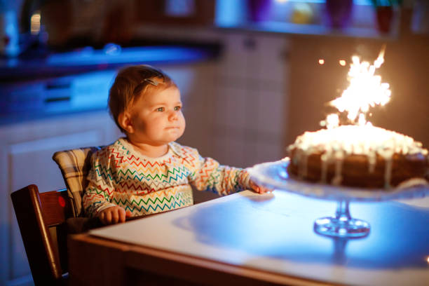 linda linda garotinha comemorando primeiro aniversário. criança soprando uma vela em bolo caseiro assado, dentro de casa. festa de aniversário da família para criança adorável, linda filha - birthday cake family germany indoors - fotografias e filmes do acervo