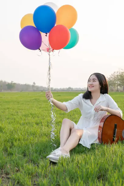 The beautiful Asian girl is cheerful with colorful balloons.