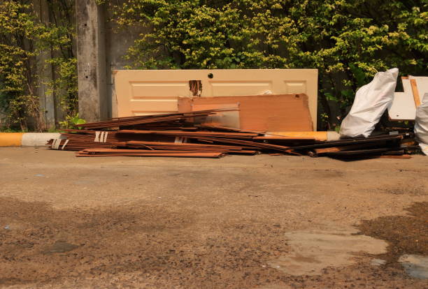 Discarded damaged door and stack of worn out plywoods are threw away in front of dump site, waiting for recycle process