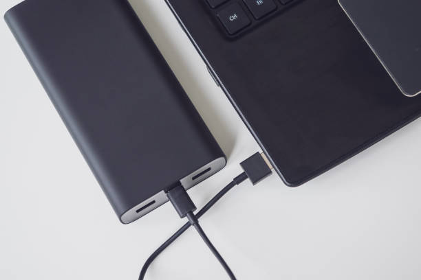 istock An open laptop is charged using a power bank via a cable. Portable modern devices. External battery, cable, USB and laptop, close-up 1212879181