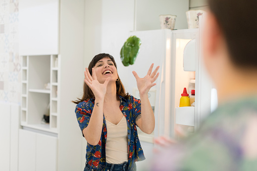 Candid moment as young woman catches green pepper to pack into the fridge