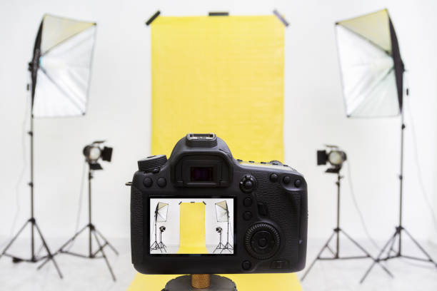istock Camera in a photo studio with yellow backdrop and light equipment 1212885891