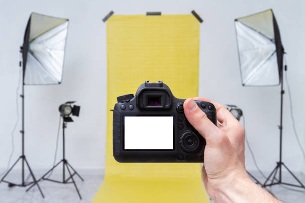 tomar fotos con la cámara en un estudio fotográfico con telón de fondo amarillo y equipo de luz - office tool flash fotografías e imágenes de stock