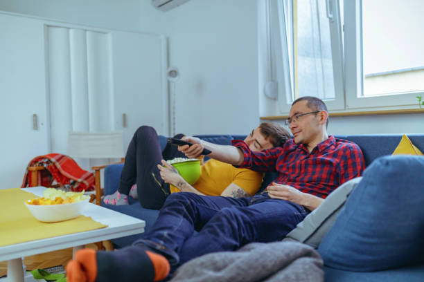istock Gay couple on the sofa changing channels and relaxing 1212887447