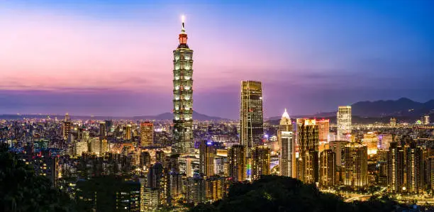 View from above, stunning view of the Taipei City skyline with the Taipei 101 tower illuminated at night during a beautiful sunset. Taipei officially Taipei City, is the capital and a special municipality of Taiwan located in northern Taiwan.