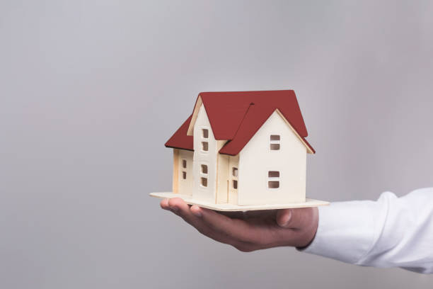 istock Small wooden toy house in hands 1212890210
