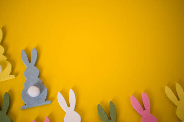 istock Easter bunnies greeting card concept on yellow background. Easter holiday background with colorful bunnies 1212892444